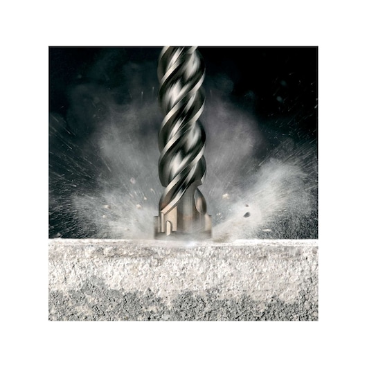 Close-up of a DEWALT DT9433 drill bit in action, drilling into concrete with dust and debris flying around.