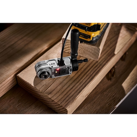DEWALT right angle drill attachment with LED, connected to a drill, placed on wooden planks.