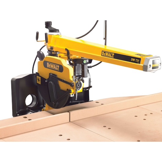 A DEWALT DW721 radial arm saw in yellow and black, positioned on a workbench and cutting through a piece of wood.