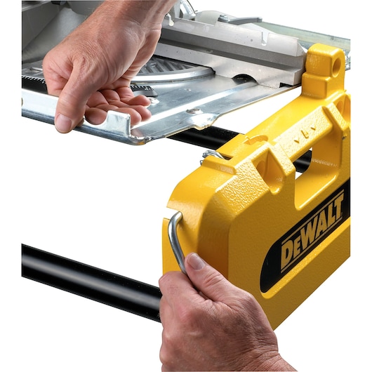 Close-up of two hands operating a DEWALT yellow power tool with a metal handle and adjusting a metal plate on the tool.