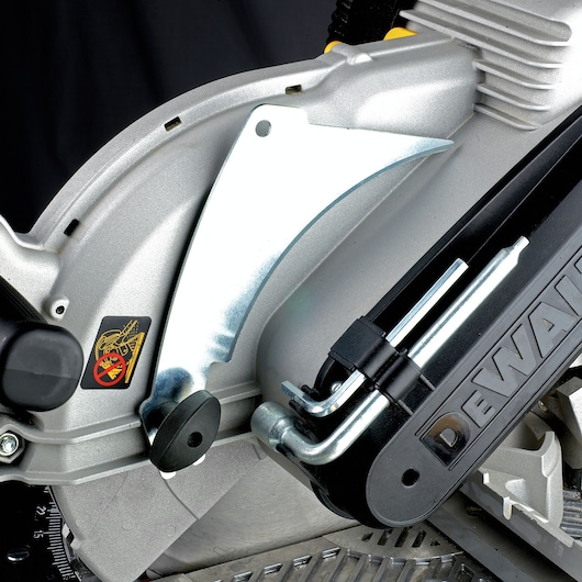 Close-up view of a DEWALT DW743N power saw, showing the metal blade guard, adjustment mechanisms, and safety sticker on the side.