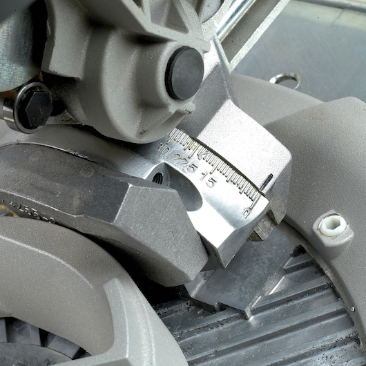 Close-up view of a metal component on a DEWALT power tool, featuring a beveled angle gauge with numerical markings from 0 to 30 degrees.