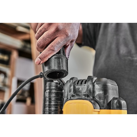 Close-up of a person connecting a power cord to a DEWALT power tool in a workshop setting.