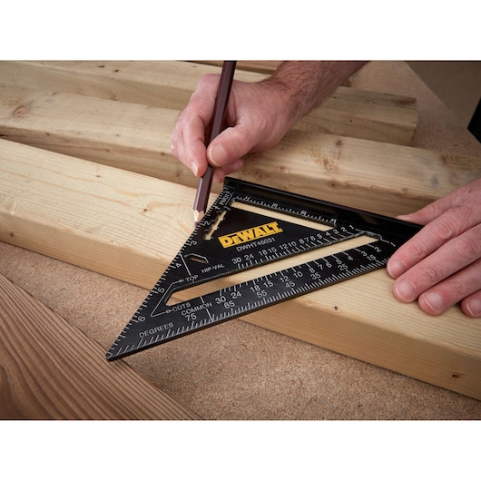 Person uses a DEWALT square and pencil to mark a straight line on a wooden plank for precise cutting.