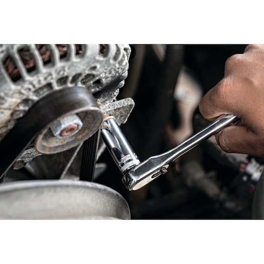 Hand using a DEWALT ratchet wrench to tighten a bolt on an engine part.