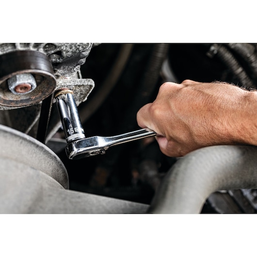 Hand using a DEWALT ratchet wrench to loosen or tighten a bolt on a mechanical part.