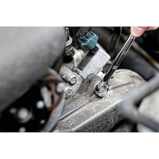 A close-up view of a DEWALT ratcheting wrench being used to tighten a bolt on an engine component.