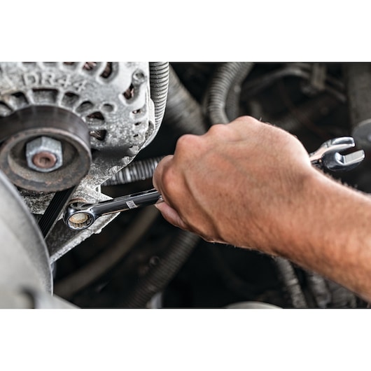 A hand uses a DEWALT ratcheting wrench to tighten or loosen a bolt on a machinery part, surrounded by mechanical components