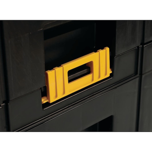 Close-up view of a DEWALT black plastic toolbox showing a yellow locking latch.