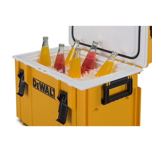 Yellow DEWALT cooler filled with ice and bottled drinks, lid open, side handles and clasps visible.