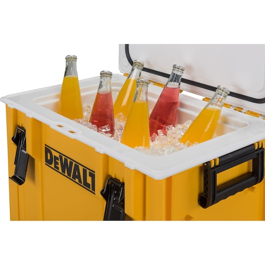 Dewalt yellow cooler with ice and glass bottles of colorful drinks inside, lid open.