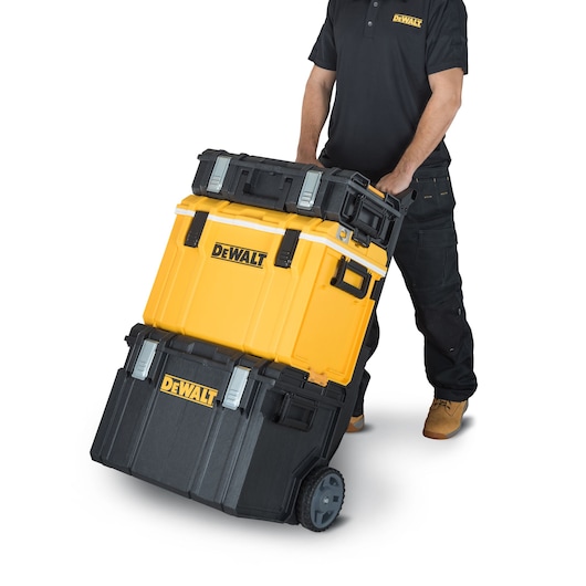 Person moving a DEWALT wheeled tool storage stack with three interlocking boxes.
