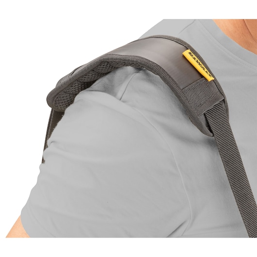 Close-up of a person wearing a padded shoulder strap with DEWALT branding, showing the strap resting on their shoulder.
