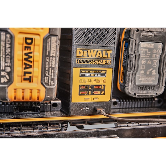 Close-up image of a DEWALT ToughSystem 2.0 module, model DWST83471, with visible battery packs and charging indicators. The module is connected via a cable and displays clear DEWALT branding and product information labels.