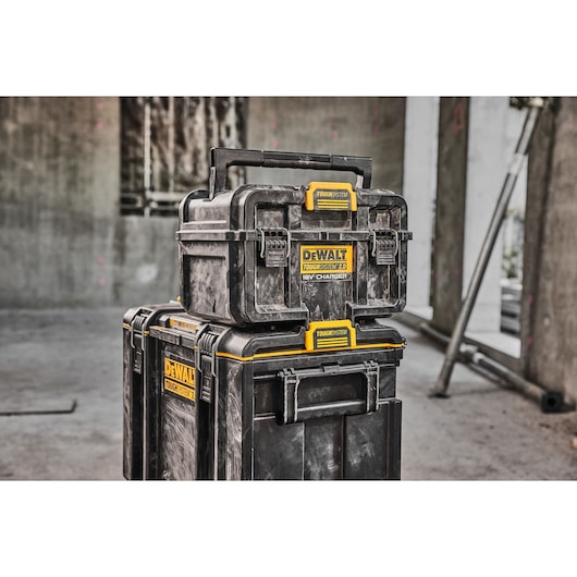 Three stacked DEWALT ToughSystem 2.0 storage boxes with yellow and black labeling, shown in a construction site setting.