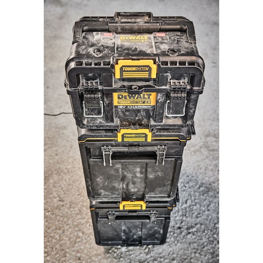 Stack of three DEWALT ToughSystem 2.0 storage boxes, including a charger box at the top, placed on a concrete floor.
