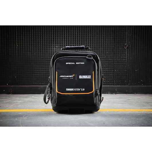 Black DEWALT Toughsystem 2.0 McLaren special edition backpack on concrete floor, featuring brand logos.