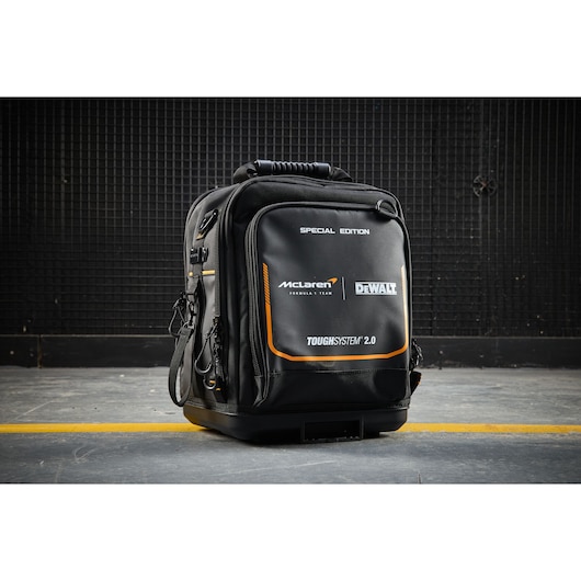 DEWALT ToughSystem 2.0 backpack, McLaren edition, black and orange, shown on concrete floor.