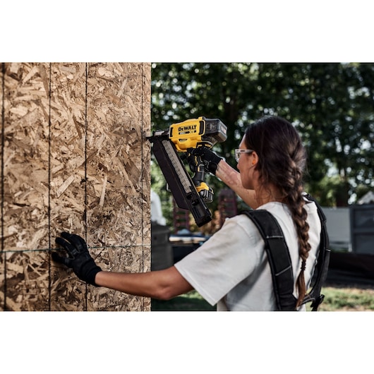 Person using DEWALT nailer DZN930-XJ, DZN930 on wood panel outdoors. Product category: Photography.